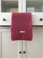Close-up detail of soft pink knit wool scarf hanging on cabinet showcasing texture. - Rose Pink