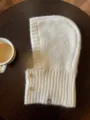 Detalle de primer plano de acogedor pasamontañas de punto crema con botones y textura. - Marfil