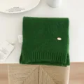 Vista detallada de bufanda de punto de lana verde lisa, con textura suave y estilo acogedor. - Verde