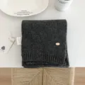 Vista detallada de bufanda de punto de lana gris oscuro, accesorio de invierno minimalista. - Gris