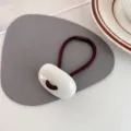 Minimalistische ovale haarelastiek met witte acrylparel, elegante bruine paardenstaart. - crème
