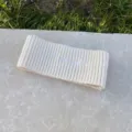Nahaufnahme des weißen Strick-Wollstirnbandes mit weicher Textur und gotischer Stickerei. - Beige