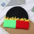 Nahaufnahme der bunten Strickmütze mit auffälligem Farbdesign und dekorativen Fransen. - Einheitsgröße / Grün-Rot-Schwarz