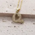Gros plan détaillé d'un pendentif lettre Q dorée avec oxydes de zirconium sur fond en pierre. - Lettre Q (Pendentif Uniquement)