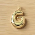 Primer plano de un bonito colgante de letra G dorada abultada en madera, abalorio. - Letra G / Dorado