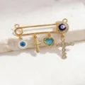 Close-up detail view of the retro gold safety pin brooch featuring evil eye charms and cross. - Style 3 (Pendant)