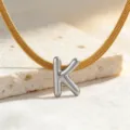 Detailansicht einer glatten Titanstahl Schlangenkette mit silbernem Buchstaben K Anhänger. - Halskette K
