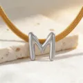 Nahaufnahme Detail der goldenen Schlangenkette mit elegantem silbernem Buchstabe M Anhänger. - Halskette M