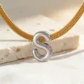 Detailaufnahme einer goldenen Schlangenkette mit silbernem Buchstaben S Anhänger, Schmuck. - Halskette S