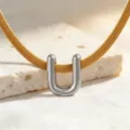 Nahaufnahme einer minimalistischen goldenen Schlangenkette mit silbernem Buchstabe U Anhänger. - Halskette U