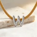 Nahaufnahme einer goldenen Schlangenkette mit silbernem W Buchstaben Anhänger für Damen. - Halskette W