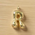 Detalle de primer plano de un bonito colgante de letra R dorada abultada para joyería. - Letra R / Dorado