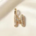 Gouden letter M hanger detail, sprankelende zirkoniastenen op glanzend gepolijst metaaloppervlak. - Letter M