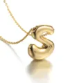 Close-up detail shot of a gold-plated puffy letter S pendant necklace with fine chain. - S