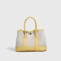 Detalle del bolso de lona amarillo con finos acabados en cuero y asas dobles muy resistentes. - Amarillo