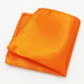 Close-up toont de gladde satijnen textuur en nette fijne stiksels van dit oranje pochet. - Oranje
