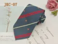 Detailed view of the navy blue JK uniform tie featuring red stripes and delicate crown embroidery. - JKC-07