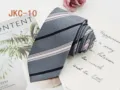Detail shot of grey JK uniform tie featuring elegant pink and black diagonal stripes fabric. - JKC-10