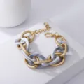 Detailansicht eines schicken mehrlagigen Metall- und Marmoracryl-Armbands im Retro-Look. - Gold Metall Grau Marmor Acryl / Goldgrau