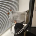 Bolso de hombro gris moderno para mujer con correas finas y elegante colgante de abalorio naranja. - Plateado