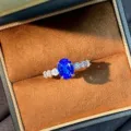 Primo piano dettagliato dell'elegante anello con gemma blu e pietre scintillanti nella scatola. - n.5 / Blu