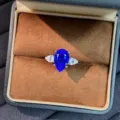 Primo piano dettagliato dell'elegante anello con gemma blu tagliata a pera e pietre laterali. - n.5 / Blu di Laboratorio