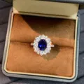 Detailed close-up of a stunning royal blue sapphire ring with sparkling white stone halo in box. - Size 5 / Royal Blue