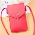 Détail de sac bandoulière rouge pour téléphone avec fermoir cœur doré et texture fine. - Rouge