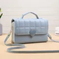 Gedetailleerd overzicht van de lichtblauwe gewatteerde crossbodytas met hartsluiting en ritsen. - Blauw