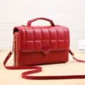 Détail de sac bandoulière matelassé rouge, fermoir cœur élégant et fermetures éclair pratiques. - Rouge