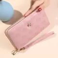 Portefeuille long rose à double fermeture éclair avec motif de camélia et dragonne élégante. - Rose