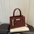 Klassische burgunderrote Henkeltasche mit schickem Drehverschluss und elegantem Perlenanhänger. - Mit Anhänger / Rot
