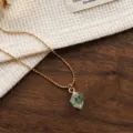 Collana con catenina di perline dorate e ciondolo in cristallo verde, dettaglio elegante. - Collane in quarzo verde irregolare