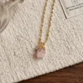 Closeup of natural raw rose quartz crystal pendant necklace with delicate gold chain and charm. - Irregular Rose Quartz Necklaces