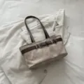 Bolso de hombro vintage de lona con diseño de hebilla de cinturón marrón contrastante. - Caqui