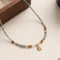 Primo piano di una delicata collana di perline con pietre naturali e pendente a cuore dorato. - Collana di Perline Cuore (2603ZK41544XL)