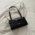 Black patent leather shoulder bag for women, stylish underarm handbag with buckle strap detail. - Black