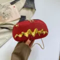 Einfallsreiche rote Damen Umhängetasche mit goldenem Wellenmuster und eleganter Metallkette. - Rot