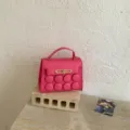 Pink top handle shoulder bag with unique round embossed design and gold tone hardware. - Pink