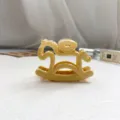 Vue détaillée d'une pince à cheveux cheval bascule jaune avec design de pièce, accessoire. - 8cm Size / Jaune