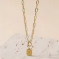 Primo piano dettagliato della collana dorata con ciondolo quadrato e chiusura a T. - Collana