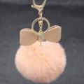 Close-up of fluffy pink pom pom keychain with rhinestone bow and gold metal clasp detail. - Bowknot Style - Artificial Rex Rabbit Fur / Pink