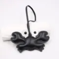 Detailed closeup of a cute black leather crab bag charm with black strap and white eyes. - Black