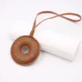 Handcrafted leather donut keychain charm detail view, showing colorful stitches and hanging strap. - Strap Style / Brown
