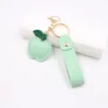 Detailed close-up of the green apple leather keychain with metal hardware and wrist strap. - Green