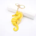 Gele lederen zeepaardje sleutelhanger en tassenhanger met gouden hardware details. - Geel