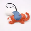 Detail closeup shot of a cute orange and blue leather elephant bag charm with black strap. - Orange - Blue Wings