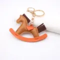 Leather rocking horse keychain bag charm with gold hardware and orange accent detailing. - Coffee