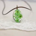 Detalle en primer plano del collar colgante de flores secas ovaladas DIY con tono verde. - Verde