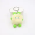 Close-up detail of the fluffy yellow plush bunny keychain featuring green ears and big eyes. - Beige